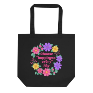 Motivational black tote bag with quote: Choose happiness every day. Pink text with purple, pink and yellow floral wreath with green leaves and foliage.