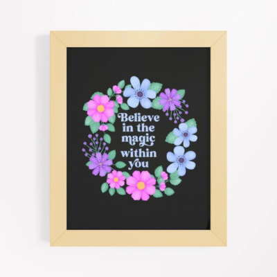 Motivational wall art with purple and blue floral wreath on black background with text: Believe in the magic within you.