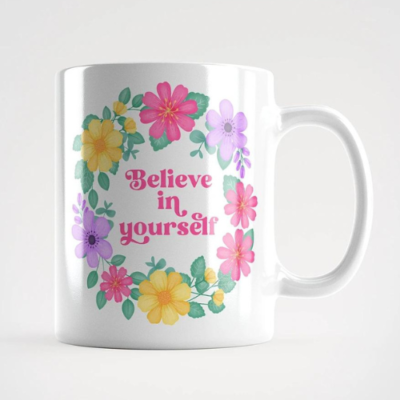 Motivational mug with quote: Believe in yourself. Pink text with violet, pink and yellow floral wreath with green leaves and foliage.