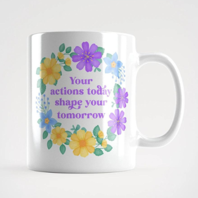 Motivational mug with quote: Your actions today shape your tomorrow. Purple text with blue, yellow and purple floral wreath with green leaves and foliage.