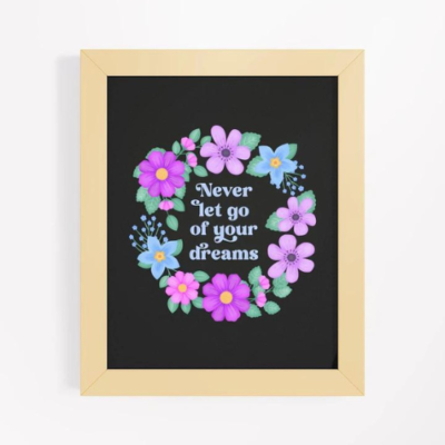 Motivational wall art with quote: Never let go of your dreams. Text with blue and violet flowers and foliage wreath on a black background and wooden frame.