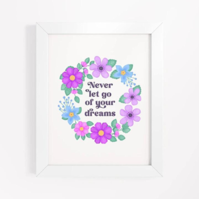 Motivational wall art with quote: Never let go of your dreams. Text with blue and violet flowers and foliage wreath on a white background.