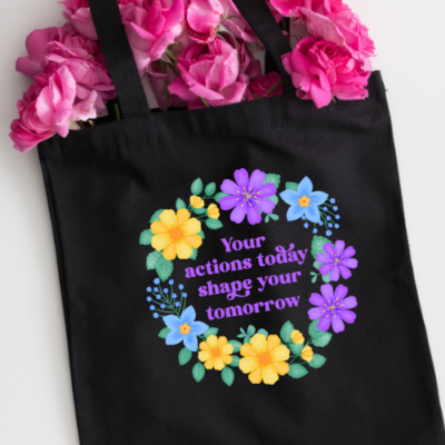 Motivational black tote back with vibrant yellow, purple and blue flowers with text: Your actions today shape your tomorrow.