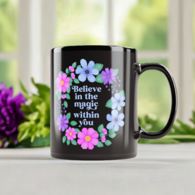 Black mug with floral wreath and motivational quote reads: Believe in the magic within you.